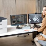 Stampante Xerox® VersaLink® C620 sul posto di lavoro Donna in un ufficio accanto alla stampante Xerox® VersaLink® C620